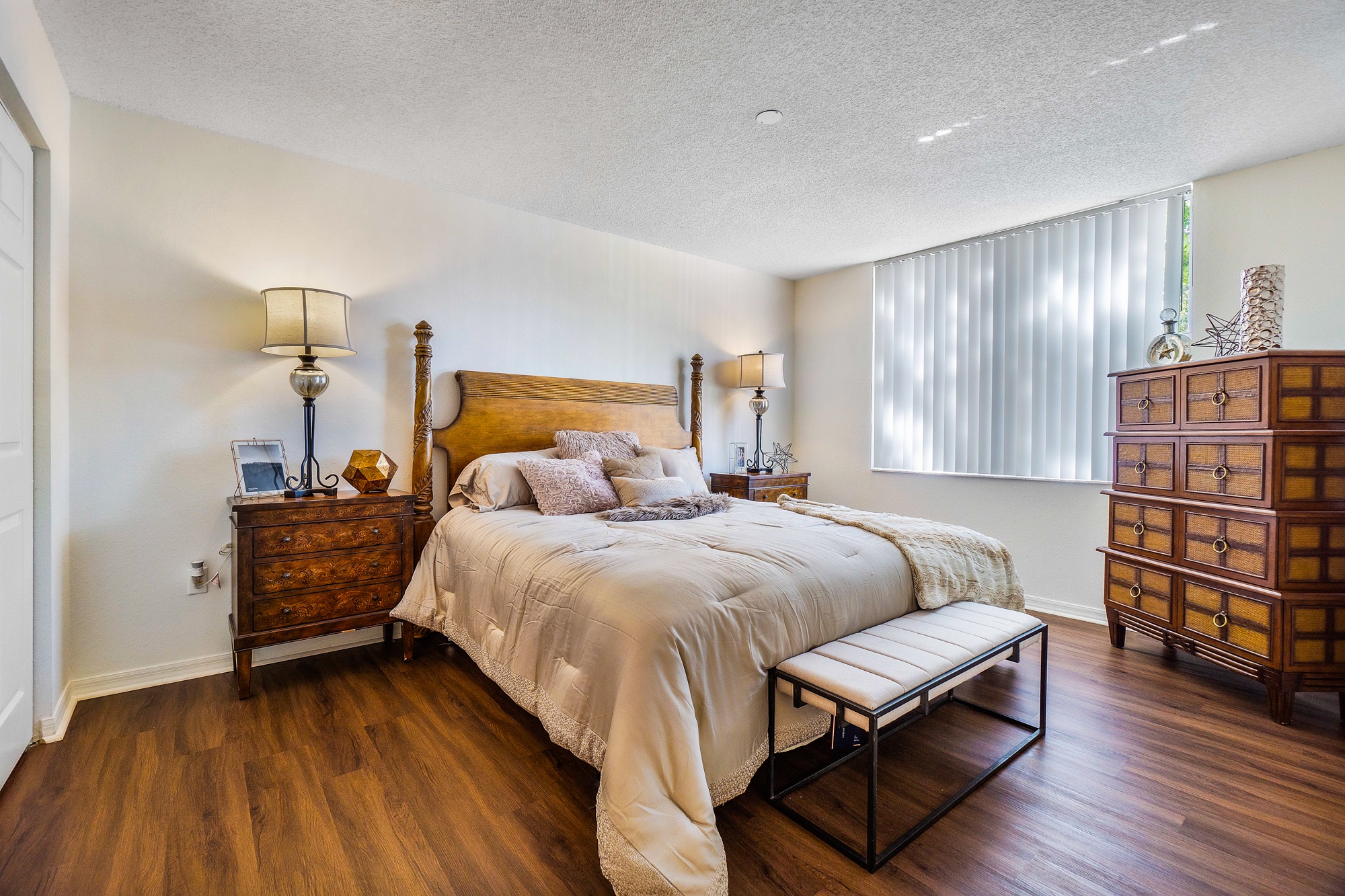 A bedroom with a large bed and a wooden dresser.